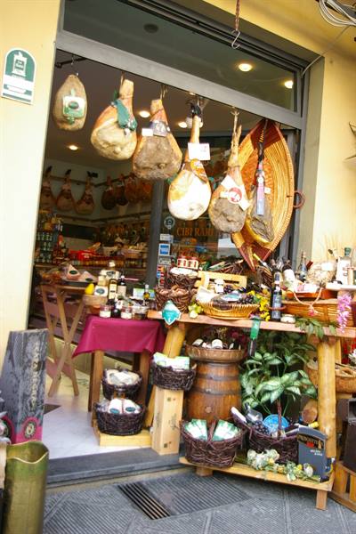 Deli shop with hanging hams and baskets of local goods at entrance