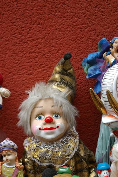 Clown doll with golden hat and fluffy white hair among colorful figurines