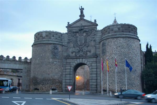 Bisagra Gate in Toledo: stone towers with coat of arms and flags