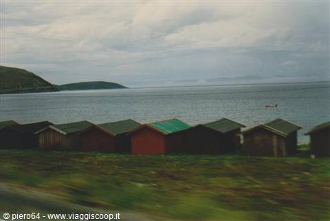 Wooden fishing huts in red and green facing the cold sea, grey clouds above