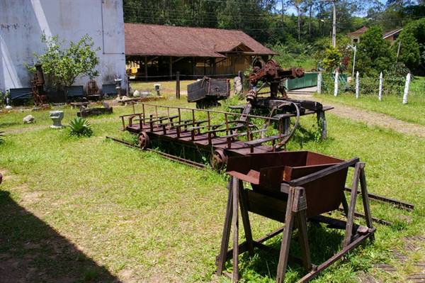 Rusty mining cart and rail wagon displayed on tracks in a grassy museum yard