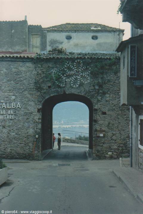 Stone gate with luminous flower sign, two people look at the sea