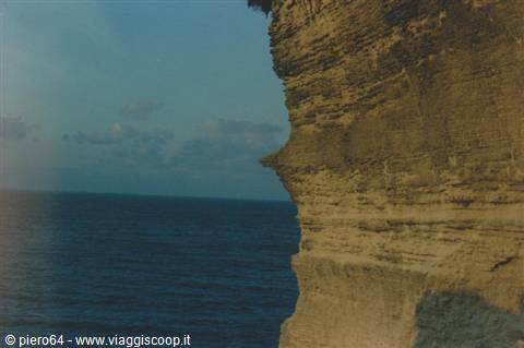 Layered limestone cliff above blue sea, clear sky at Etretat