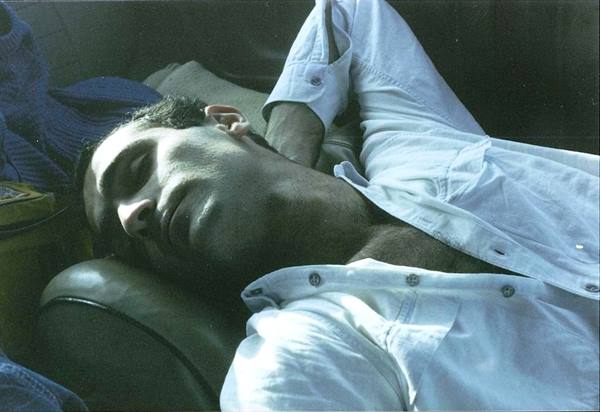 Man sleeping on suede seats, sunlight on face and white shirt