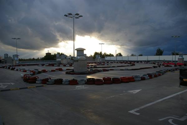 Go-kart track with red and white tires under threatening stormy clouds
