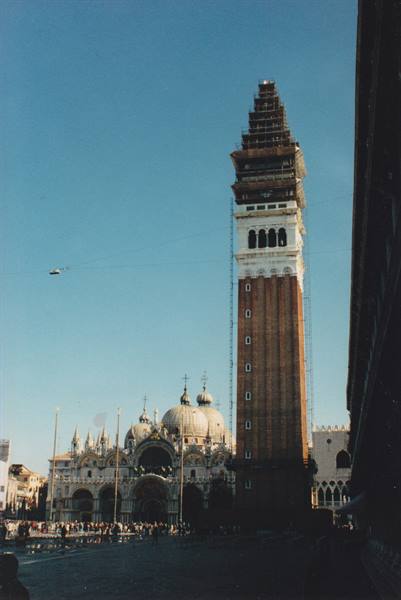 St Mark's bell tower under restoration in the square, domed basilica beneath blue sky