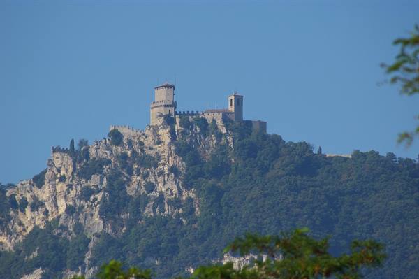Guaita tower of San Marino perched on the rocky cliff under blue sky