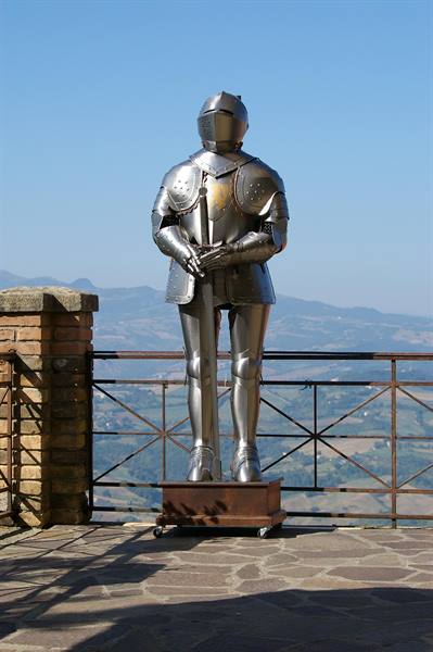 Steel knight armor on a terrace overlooking hills, likely San Marino