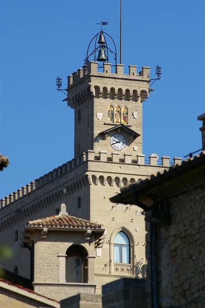 Crenellated clock tower of San Marino's Public Palace with bell and mosaic