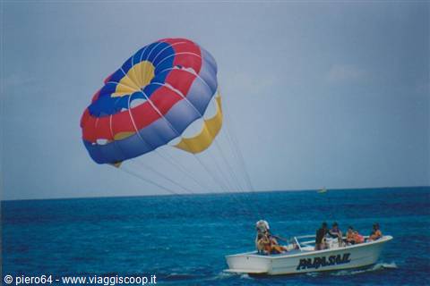 Parasailer under red and blue canopy towed by the Papa Sail motorboat