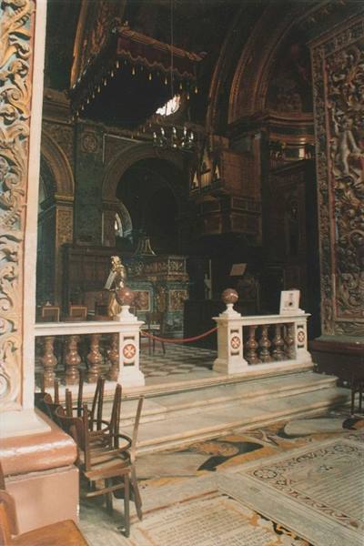 Baroque church interior: altar, marble balustrade, wooden chairs and inlaid floor
