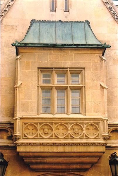 Stone balcony with carved flowers and green copper roof on facade