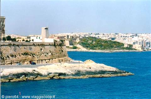 Limestone walls and watchtower on Malta's harbour, bright blue sea