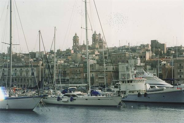 Sailboats moored at the harbor in front of city domes and rooftops