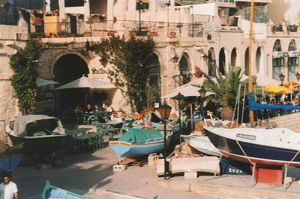 Boats hauled ashore at Jaffa port, cafes with umbrellas among stone arches