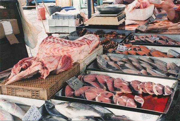 Fish market stall with fresh tuna steaks, crates and weighing scale