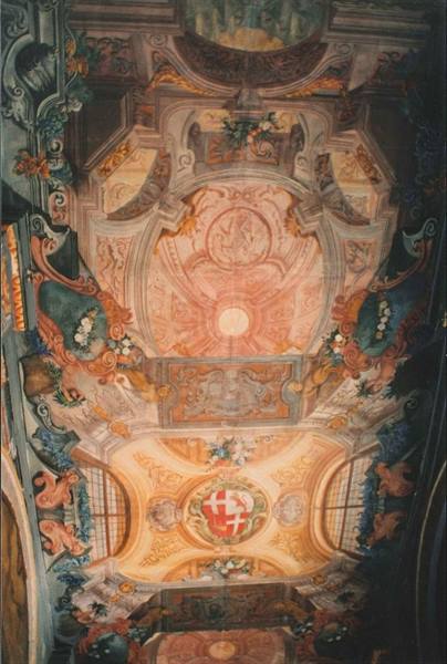 Baroque frescoed ceiling with red and white coat of arms, warm light