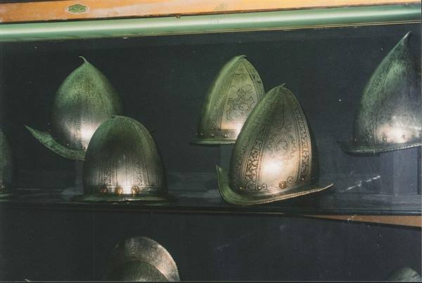 Engraved steel morion helmets displayed behind glass