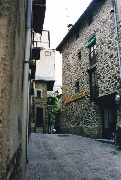 Cobbled alley between stone houses, yellow restaurant sign