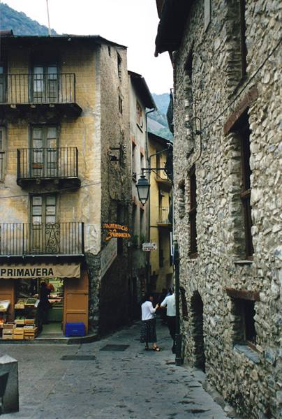 Pedestrians in a narrow stone-house alley, Primavera shop sign