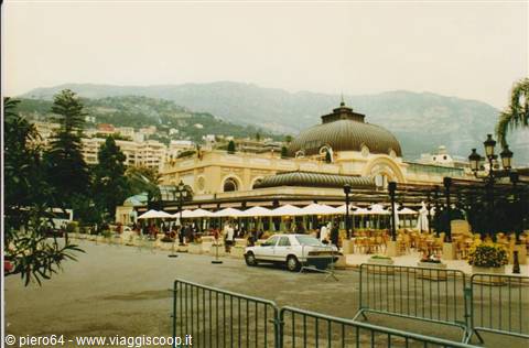 White-umbrella café terrace and metal dome with cars passing in Monte Carlo