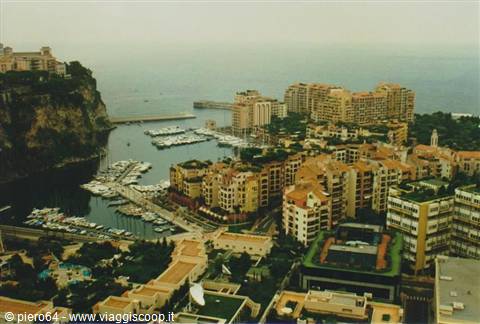 Fontvieille harbor in Monaco, boats moored among ochre buildings under grey sky
