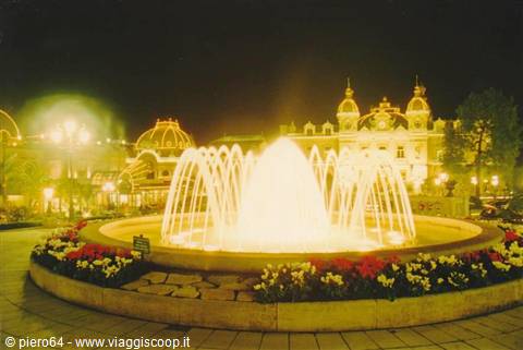 Illuminated fountain at night in front of the Monte Carlo Casino, red and white flowers