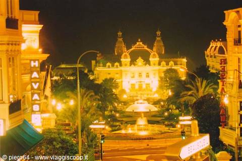 Monte Carlo Casino lit up at night with fountain and palm trees