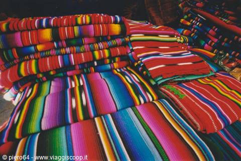 Stacks of colorful striped woven blankets at a craft market