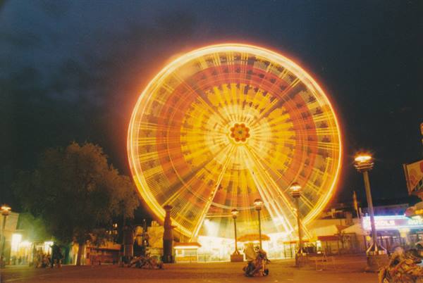 Illuminated Ferris wheel at night with blurred golden lights, amusement park