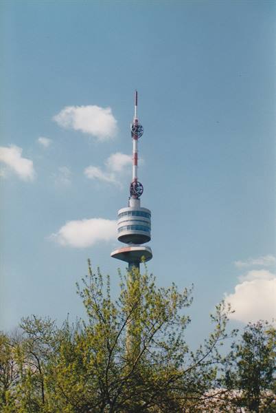 Dortmund Florianturm TV tower rising above blossoming trees under a blue cloudy sky
