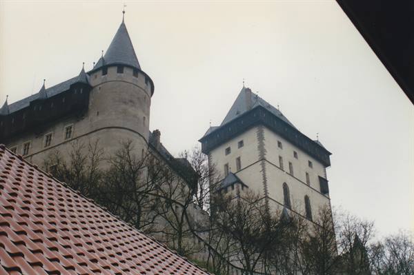 Karlštejn Castle stone towers under grey sky, red tiled roof