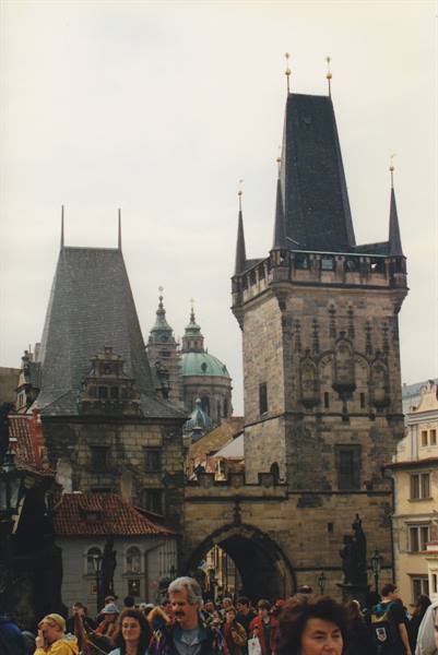 Tourists beneath the Gothic stone tower of Charles Bridge, Prague