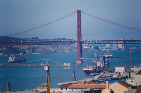 25 de Abril bridge over harbor with cranes and ships, Lisbon