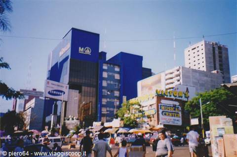 Blue high-rise with glowing signs above a busy street full of pedestrians