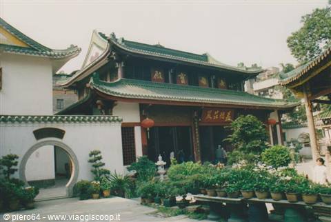 Buddhist temple with green tiled roofs, red lanterns and potted plants in courtyard