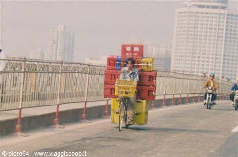 Cyclist loaded with plastic crates crossing a foggy city bridge