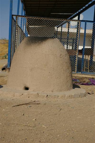Traditional clay oven under a blue metal shelter