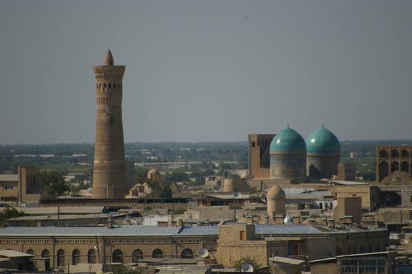 Brick minaret and turquoise domes rising over Bukhara rooftops