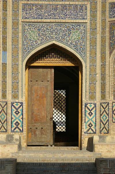 Weathered wooden door beneath an arch covered in blue and gold tiles
