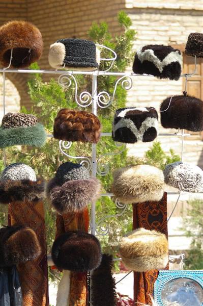 Fur hats hanging on a wrought iron outdoor display in sunlight