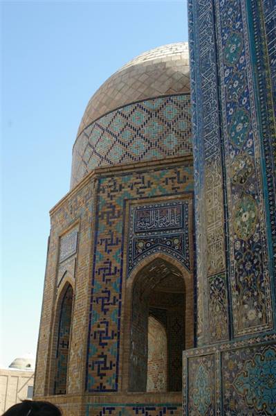 Dome and walls covered in blue and turquoise tiles under clear sky, bright sunlight