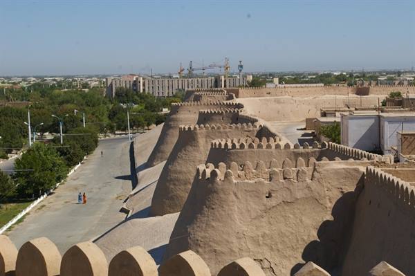 Khiva's mud-brick city walls with crenellations under bright sun