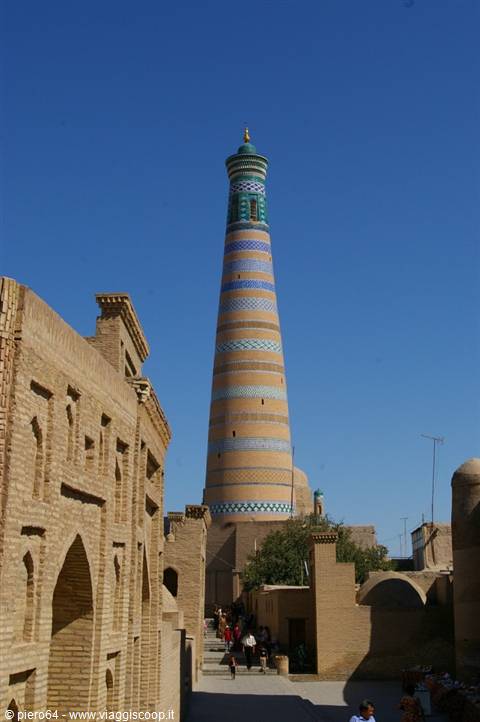 Islam Khoja minaret rises above Khiva's brick walls under blue sky