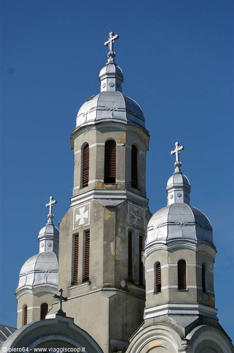 Silver domes and crosses of an Orthodox church tower against a blue sky