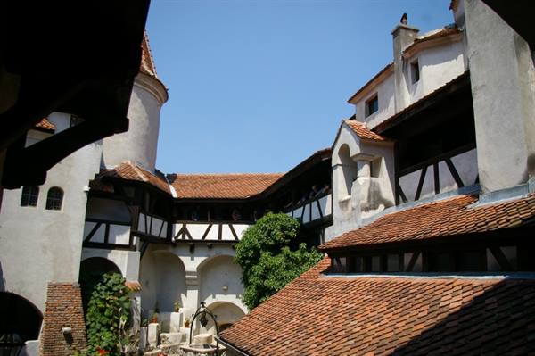 Inner courtyard of Bran Castle with whitewashed walls, timber framing and terracotta roofs