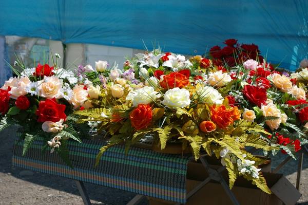 Colorful artificial flowers for sale under a blue market tent