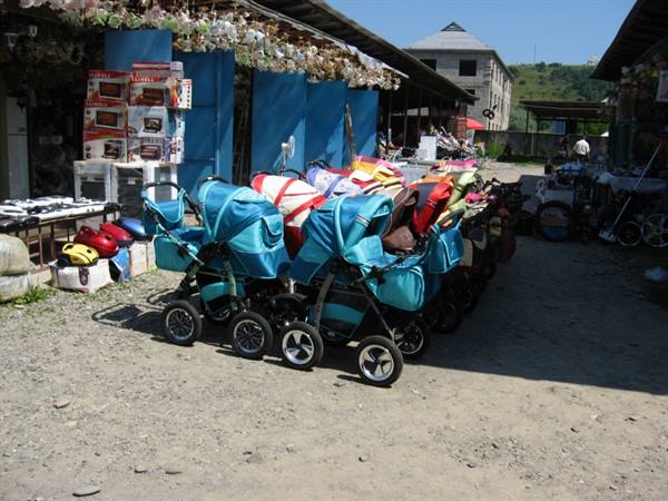 Blue strollers lined up in the shade of an open-air market