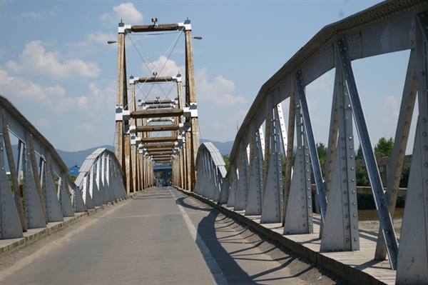 Steel truss bridge with metal beams and central wooden structure, daylight