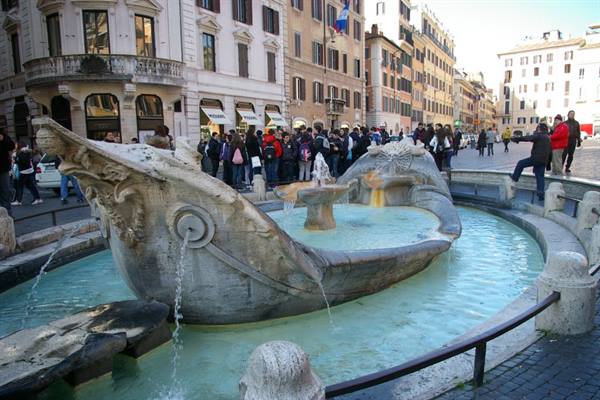 Bernini's Barcaccia fountain in Rome's Piazza di Spagna, tourists gathered around
